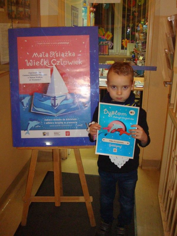 Chłopiec trzymający w ręku Dyplom Małego Czytelnika